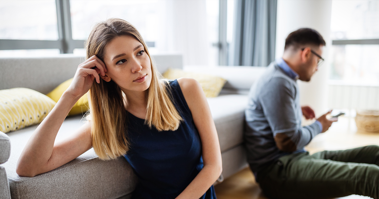 kobieta i mężczyzna siedzą oddaleni od siebie nie rozmawiając, czując samotność w związku