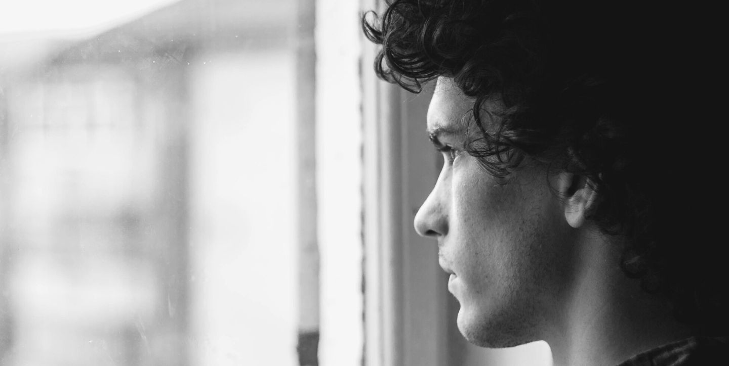 Jak poradzić sobie po rozstaniu - smutny młody mężczyzna patrzący w okno, cierpiący po rozstaniu, zastanawiający się, jak poradzić sobie po rozstaniu - Marita Woźny