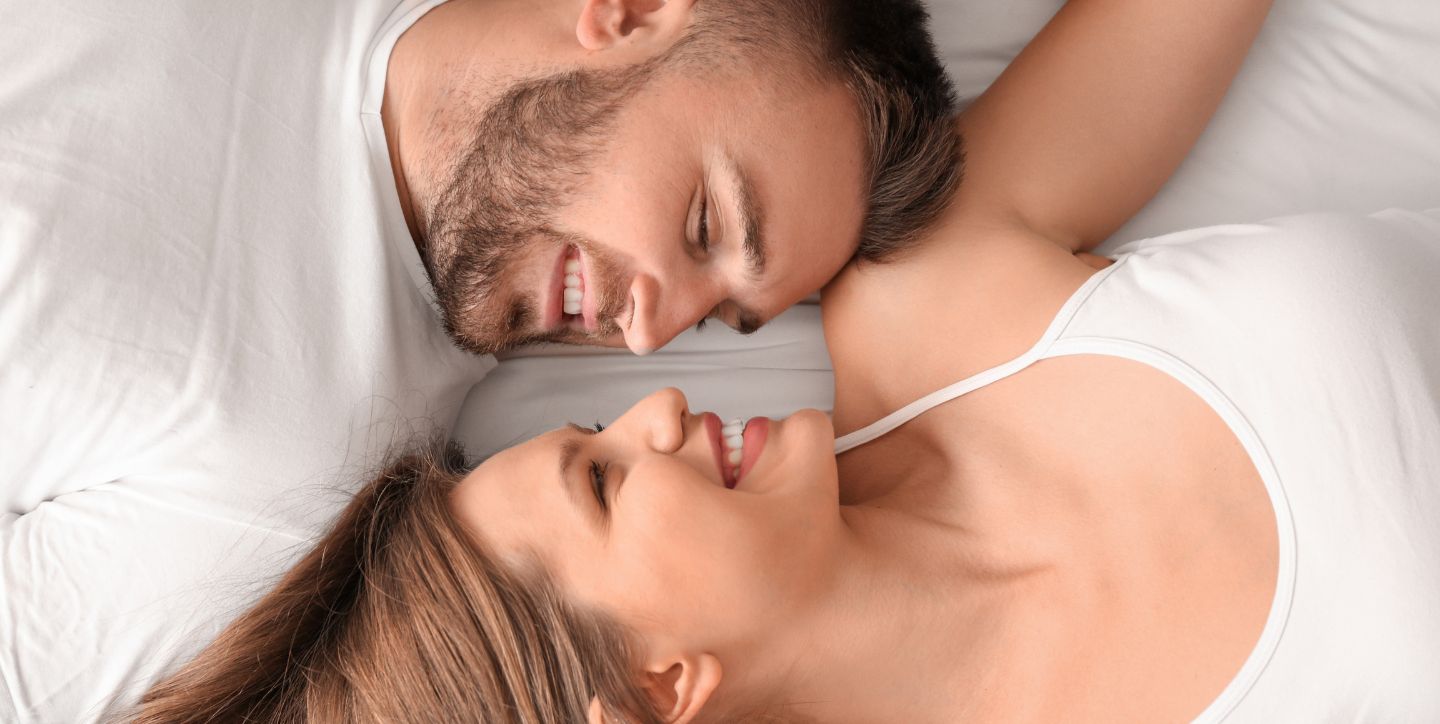 Coś specjalnie dla panów - jak doprowadzić do gorącego wieczoru - kobieta i mężczyzna leżą uśmiechnięci na łóżku patrząc sobie prosto w oczy - Marita Woźny